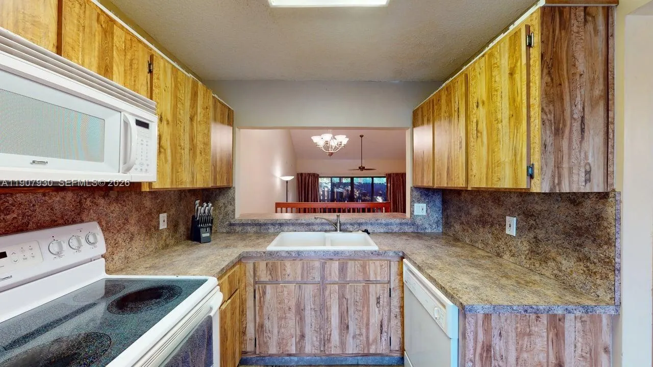 Spacious kitchen featuring rich wood cabinetry, gleaming countertops, and generous prep space — a perfect blend of charm and practicality that opens effortlessly to the dining area.