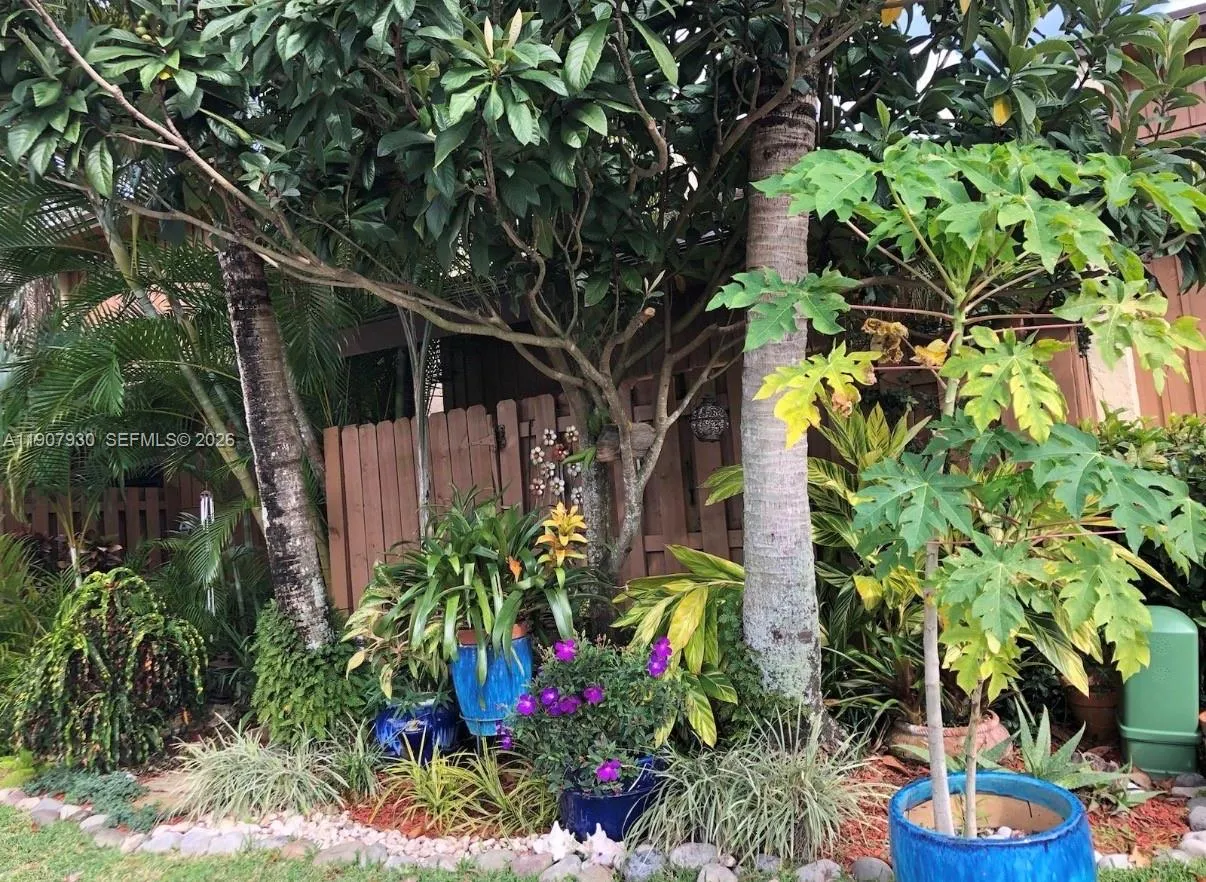 Lush, tropical entry surrounded by vibrant greenery and colorful planters a truly magical welcome that sets the tone for this serene lakeside retreat