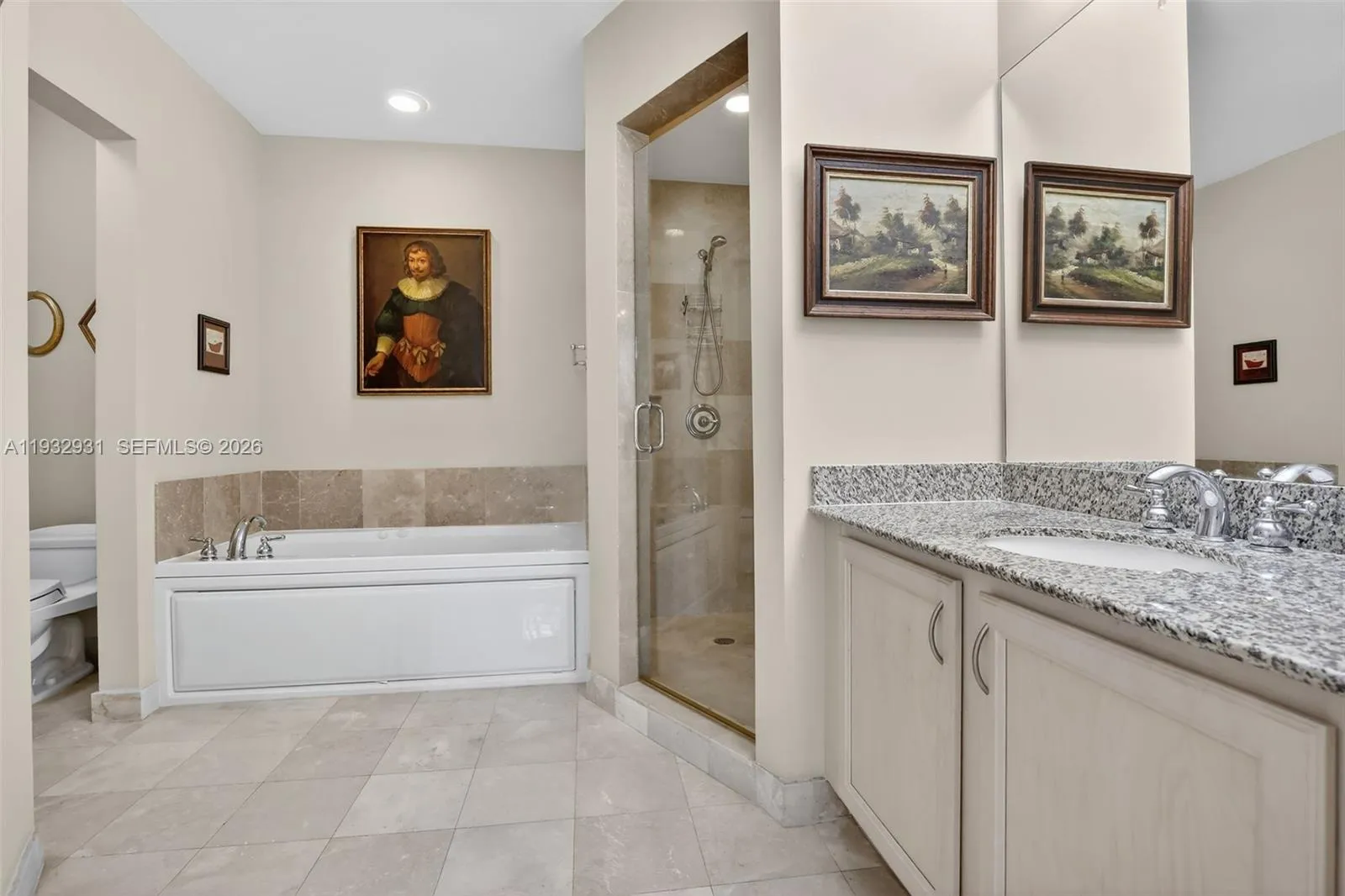 Spacious bathroom features elegant marble floors, a relaxing whirlpool but, and a separate walk-in marble shower, offering a luxurious and comfortable retreat.