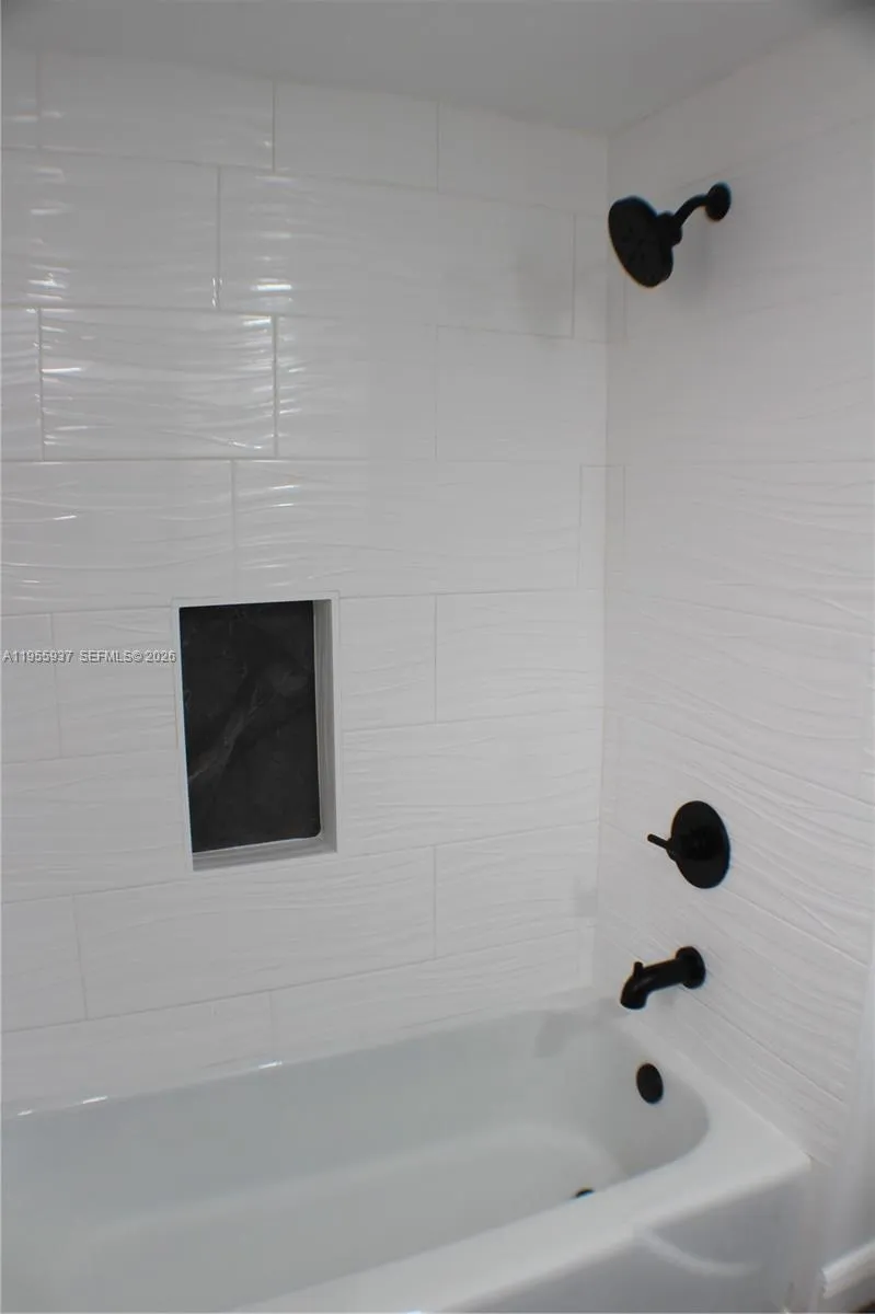 Primary bathroom shower/tub with updated tile, niche, hardware