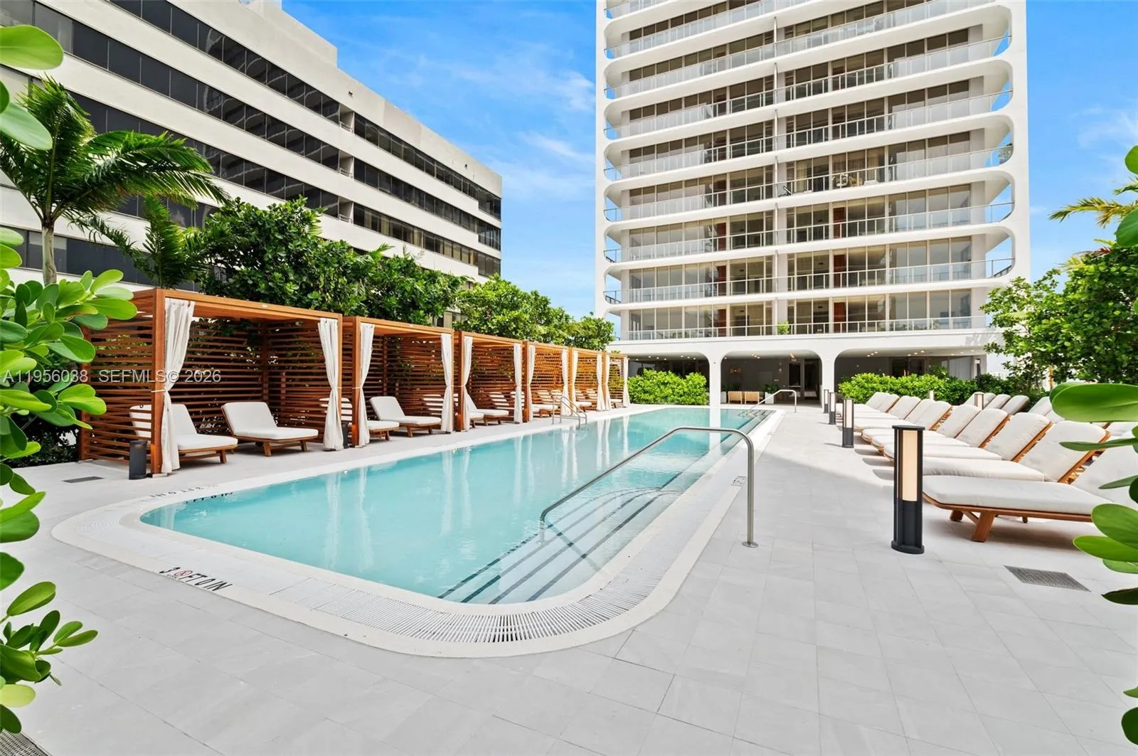 Resort-style pool deck with private cabanas, shaded lounging areas, and lush tropical landscaping at Mr. C Residences.