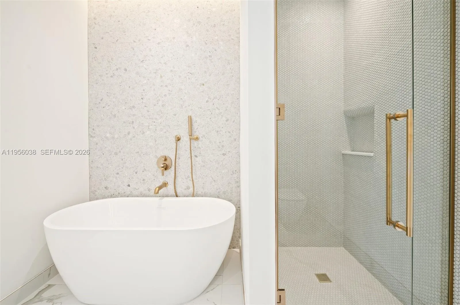 Spacious primary bathroom featuring freestanding soaking tub, glass-enclosed shower, custom vanity, and elegant designer finishes.