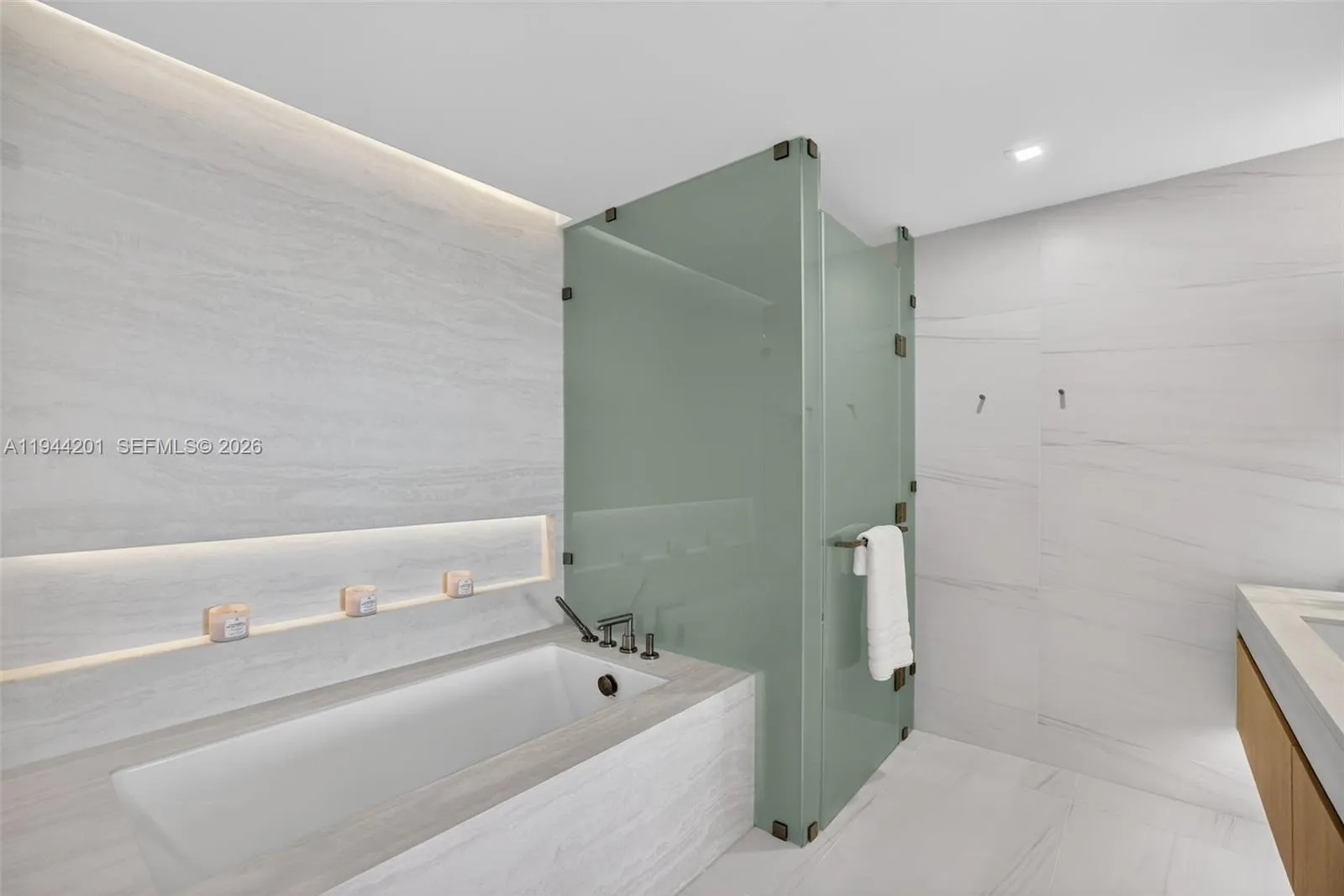 The 06 line primary bath feels like a private spa. Oversized and beautifully proportioned, it features a frameless glass walk in shower, designer soaking tub, dual vanities with stone counters, and sleek modern fixtures. Clean architectural lines, neutral luxury finishes, and generous storage for a calm, resort style retreat that complements the open coastal aesthetic of the residence.