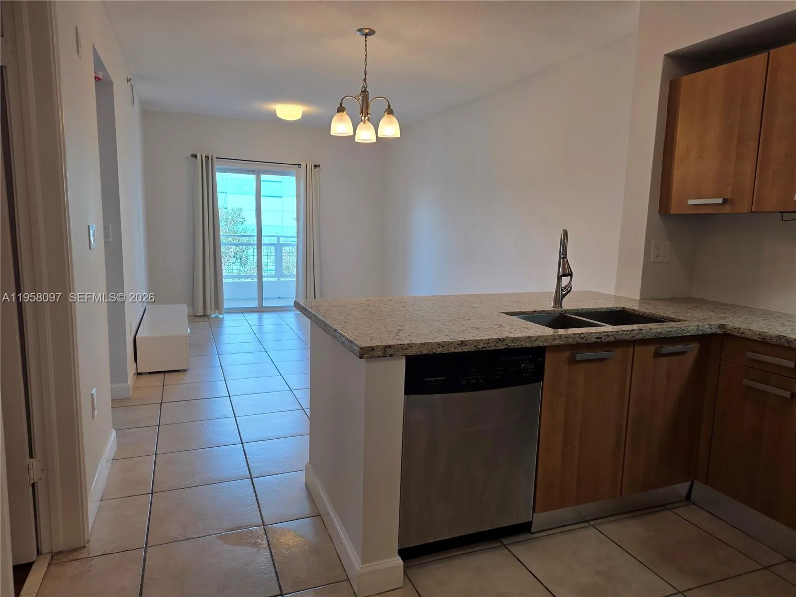 View from the kitchen into the bright living area with sliding glass doors leading to a private balcony.