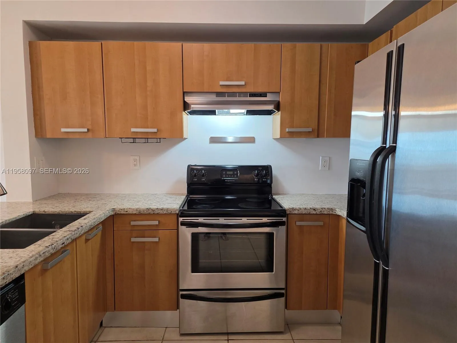 Well-equipped kitchen with stainless steel refrigerator, electric range, built-in microwave hood, and dishwasher.