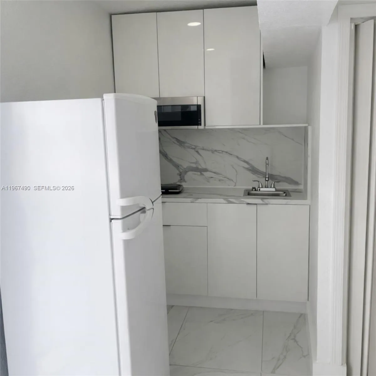 Compact kitchen with modern cabinetry, sink, and included appliances.