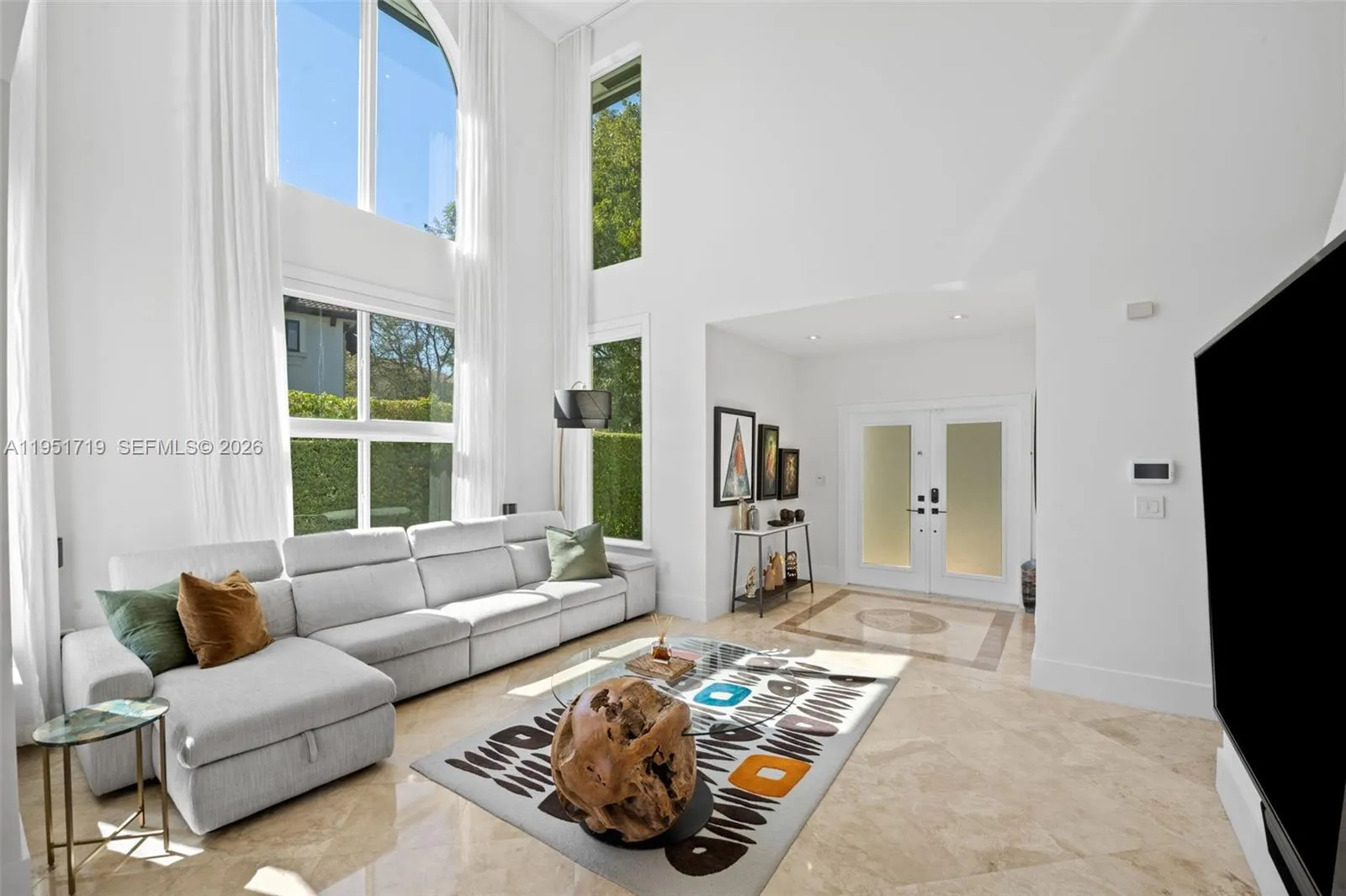 An expansive covered patio serves as a dedicated outdoor dining room, featuring polished travertine flooring, dual ceiling fans, and a direct view of the pool.