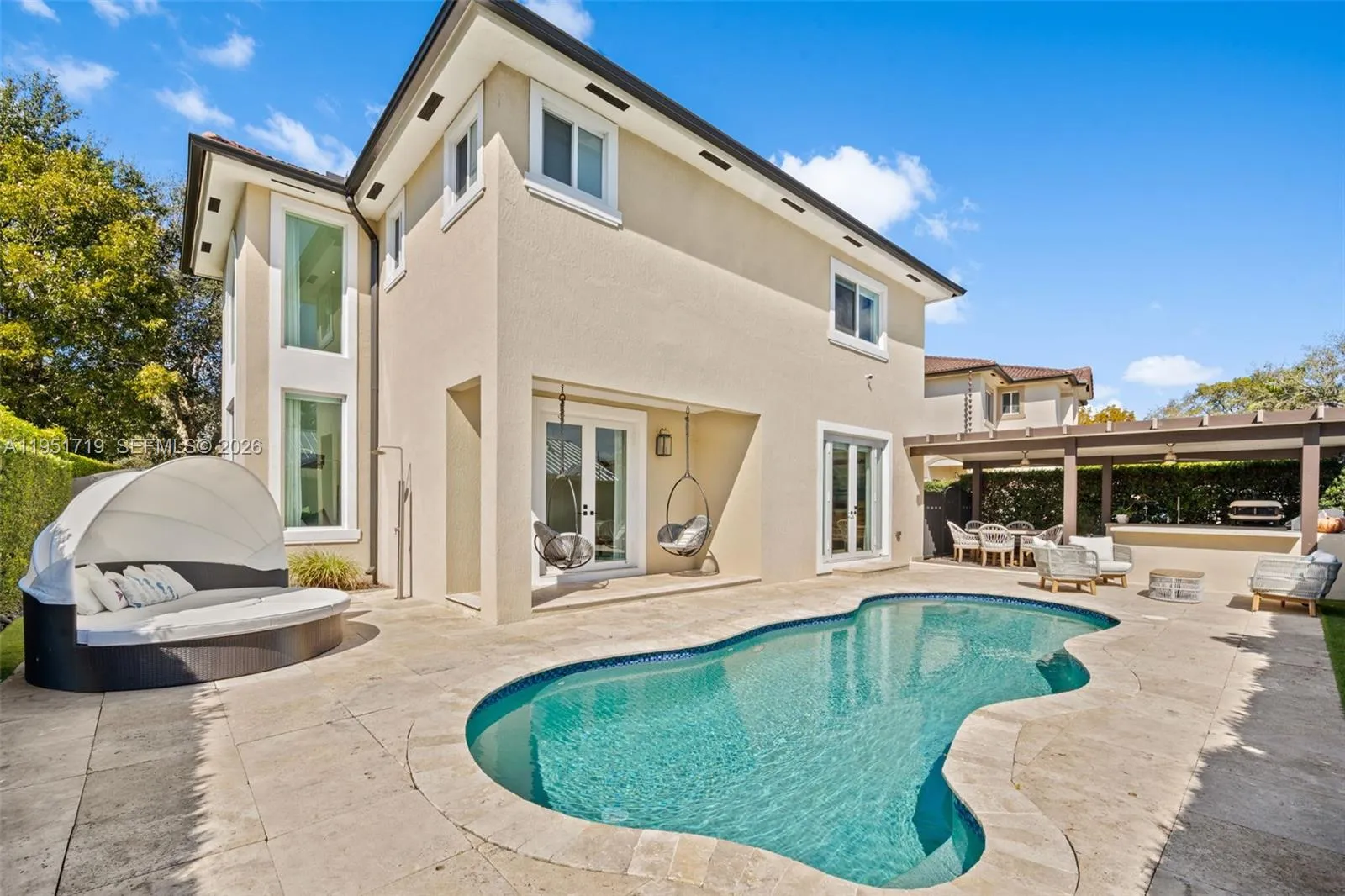This daytime view highlights the home\'s contemporary facade, manicured landscaping, and a wide paved driveway leading to the two-car garage.