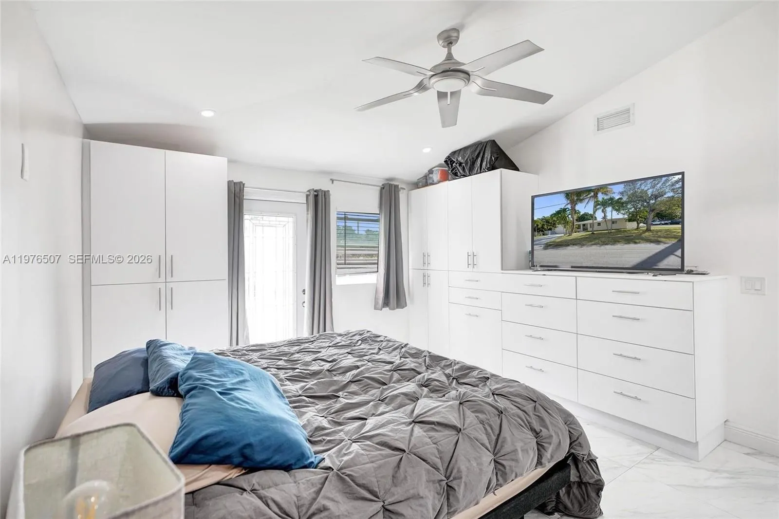 PRIMARY MASTER BEDROOM FILLED WITH LIGHT, SITTING ON 33\" X 33\" PORCELAIN TILES AND WITH A SECONDARY DOOR LEADING TO THE BACKYARD!