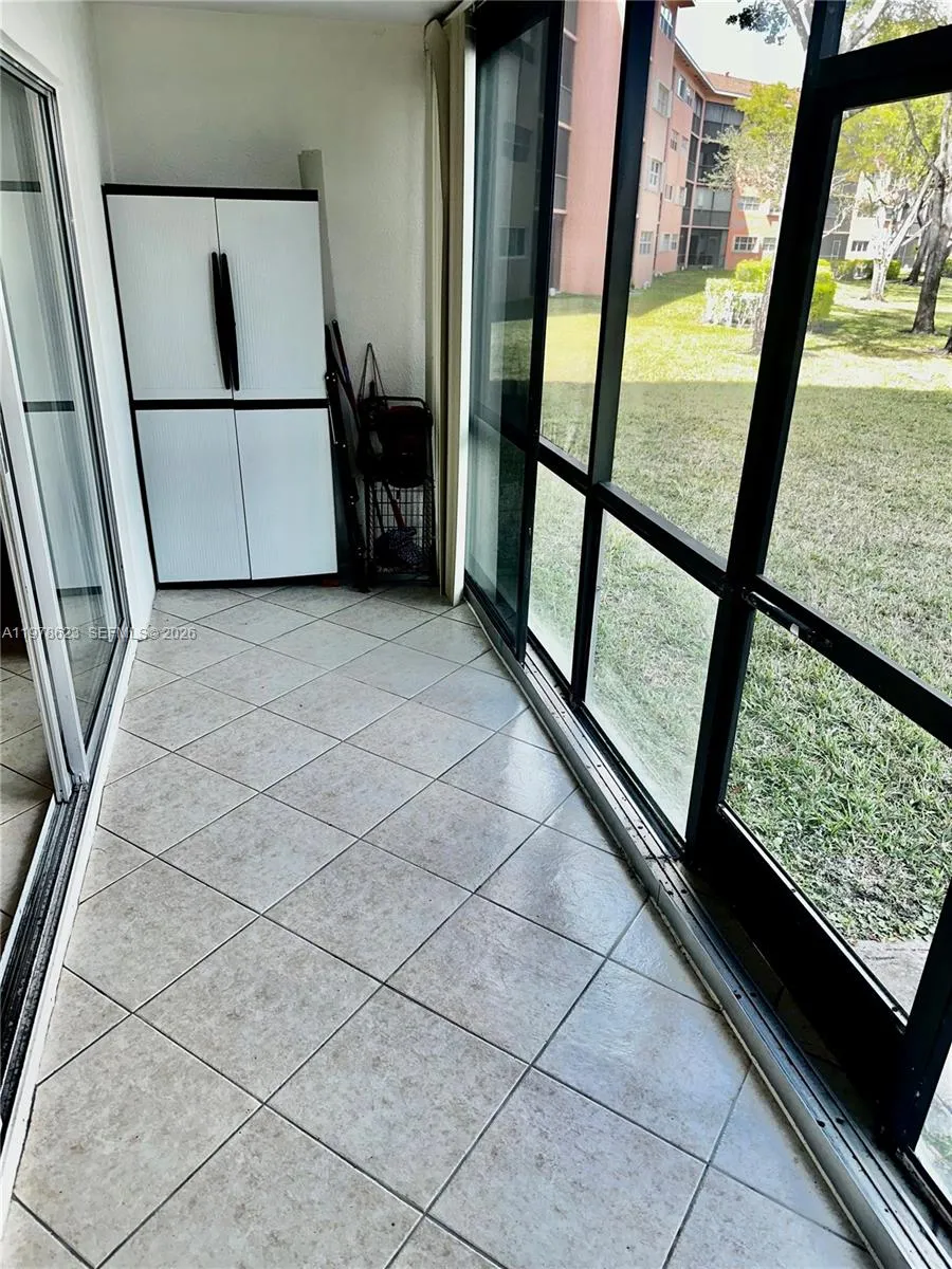 ENCLOSED TILED PATIO w/ STORAGE CABINET, GLASS SLIDERS & ACCESS DOOR TO GARDEN & LAKE