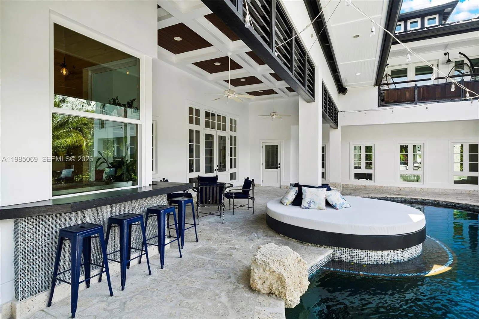 Lounge area from interior bar with windows that open to pool lounge area