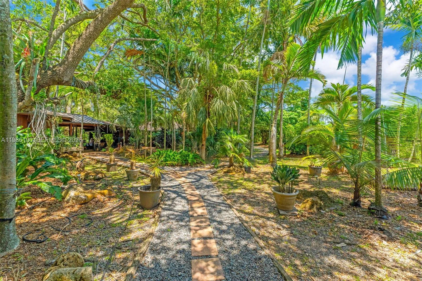 VIEW OF COVERED BREEZEWAY LEADING FROM KITCHEN TO GUEST ROTUNDA.PATHWAYS ALSO LEAD TO CARPORT FOR 3/4 CARS AND TO BARNS/PASTURES. THERE ARE 2 BARNS, A CENTER AISLE W TACK AND GROOMS AND A OPEN AIRE BARN SURROUNDED BY 3 LARGE PASTURES