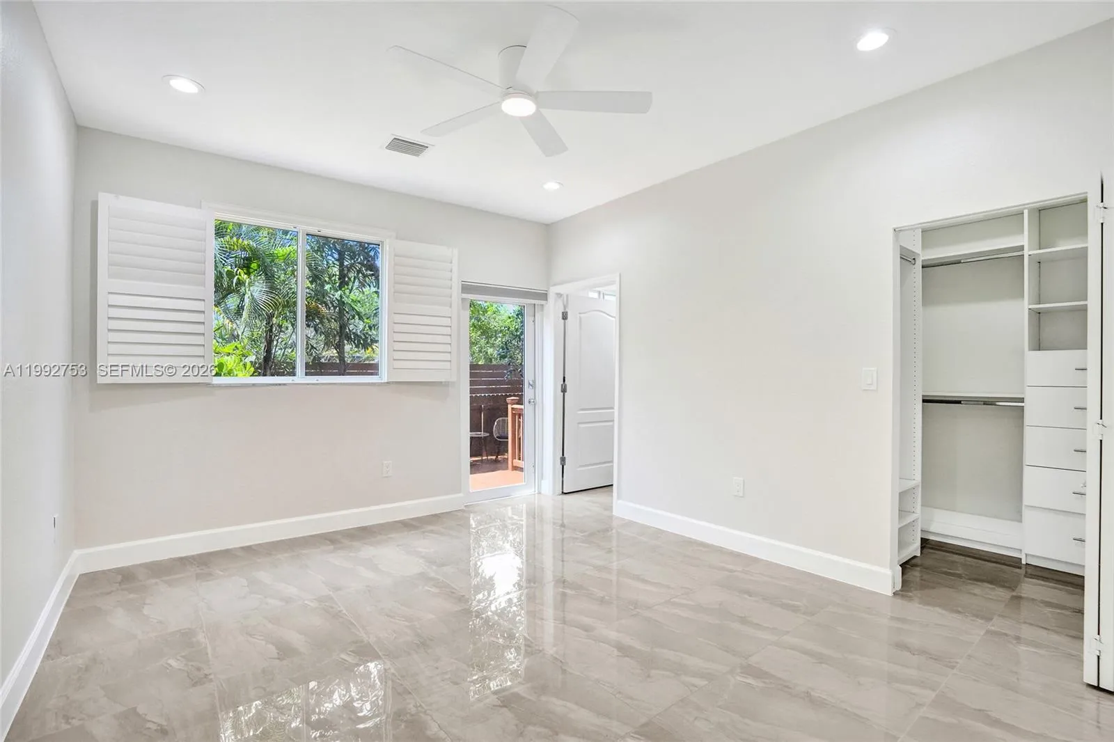 Primary bedroom, hurricane impact glass door leading out to enclosed private patio.