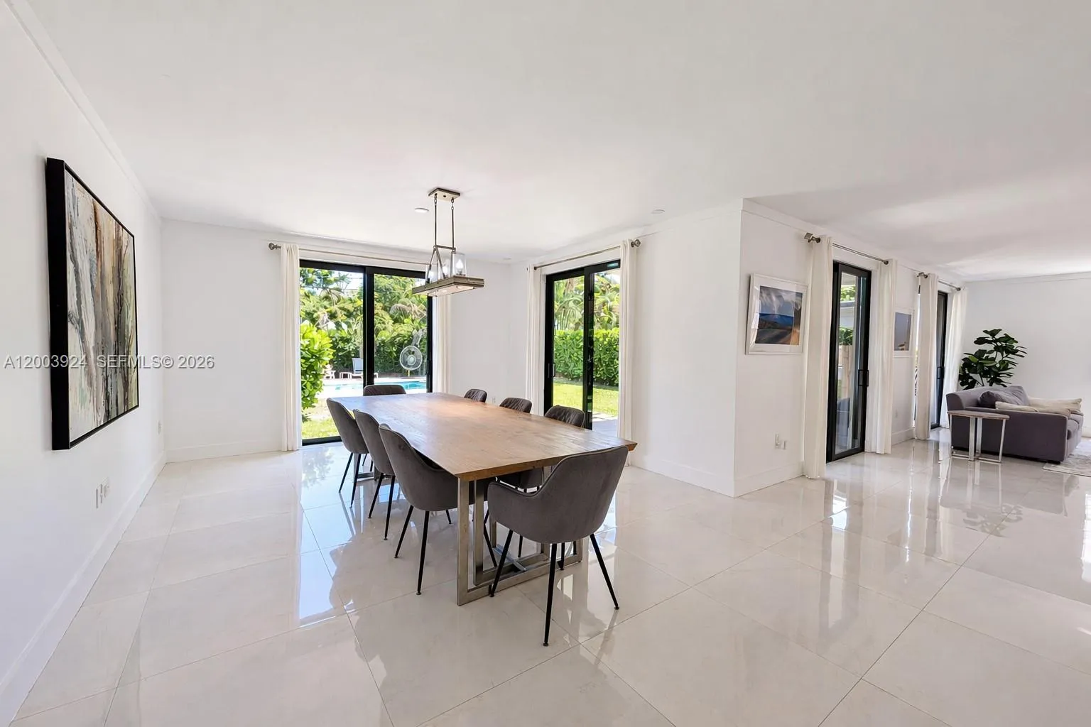 large, naturally-lit dining area with space for guests.  floor-to-ceiling doors lead to back yard terrace and pool.