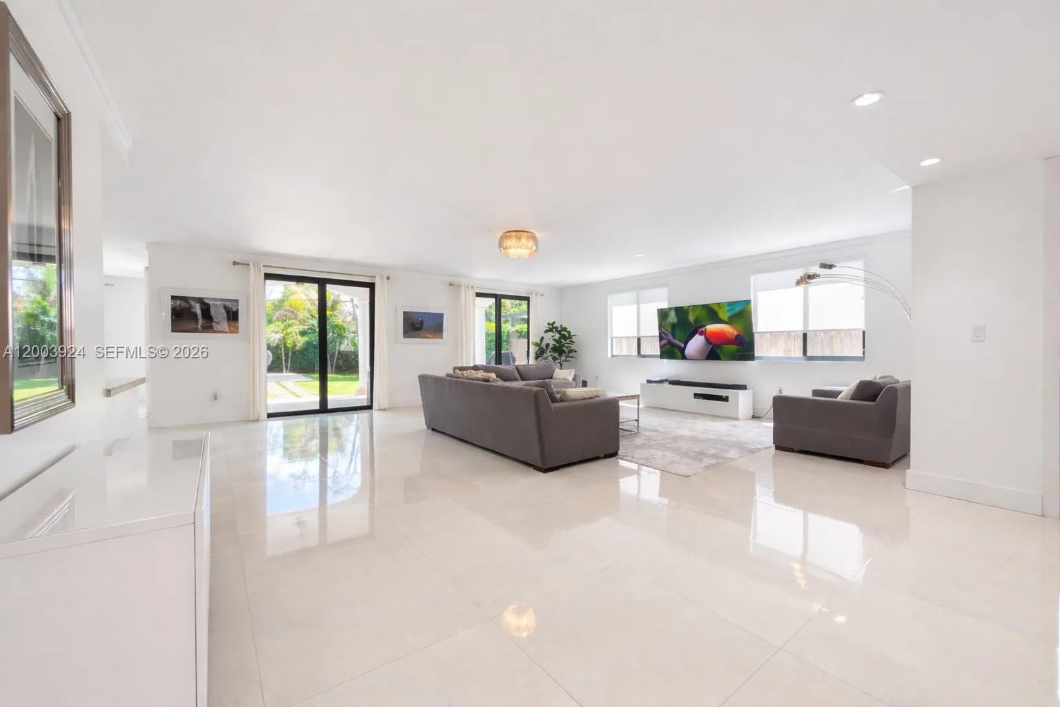 spacious open 1st floor living room, with floor-to-ceiling glass doors leading to back yard terrace and pool.