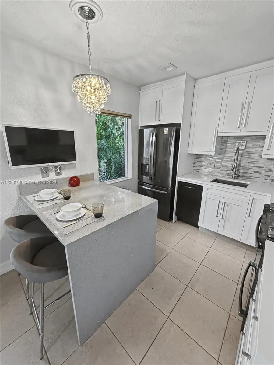 Modern white kitchen with stainless appliances, center island, and breakfast bar seating