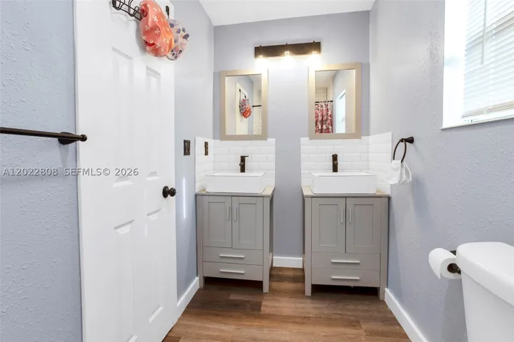 Featuring dual vanities, modern fixtures, and a beautifully tiled shower/tub combination.