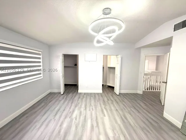 PRIMARY BEDROOM WITH TWO WALK-IN CLOSETS AND CONTEMPORARY CHANDELIER.