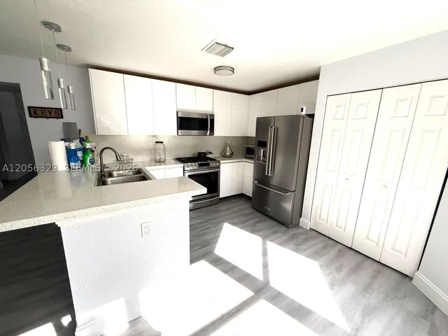 REMODELED WHITE ACRYLIC KITCHEN CABINETS AND GRANITE COUNTERTOPS