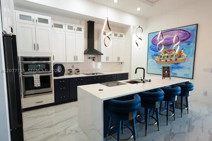 Stunning two-tone kitchen highlighting built-in double ovens, modern range hood, and luxury custom finishes