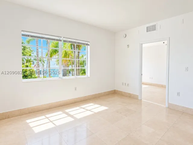 Sunlit bedroom with large window and generous floor space.