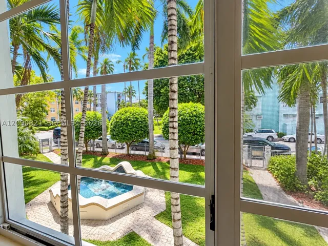 Scenic window view overlooking lush tropical foliage and gated courtyard.