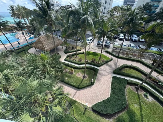 Pool area, beach access with Tiki Hut and lush landscaping.