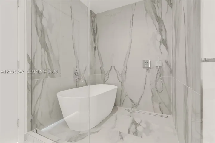 Freestanding soaking tub and glass enclosed rain shower in the primary bath