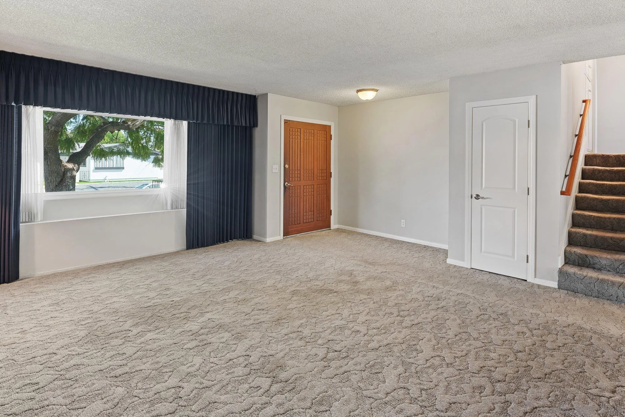 6010 Chadwick Ave, San Diego, CA 92139 Large front picture window in living room. Access stairs to top floor and below bonus room.