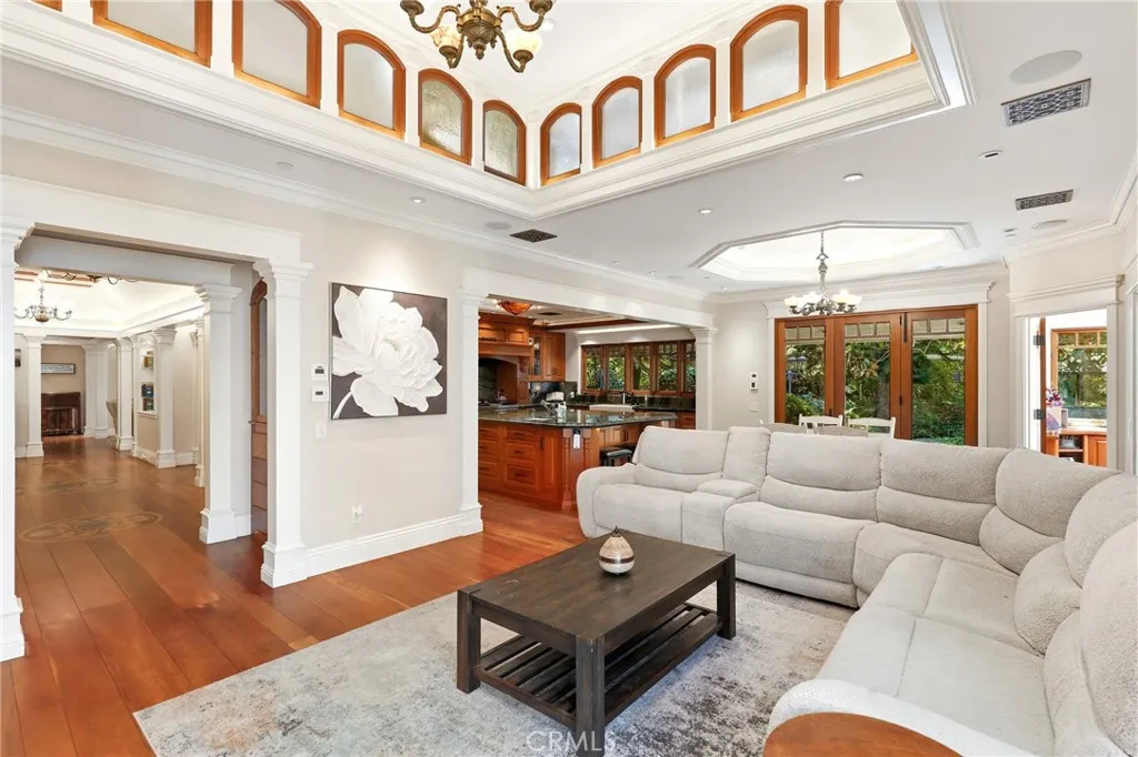 Living room with a cream sectional, dark coffee table, wood floors, and a high ceiling with clerestory windows.