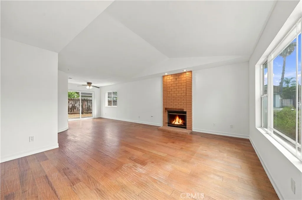 Main living room and dining area w fireplace, dual pane windows and classic wood flooring.