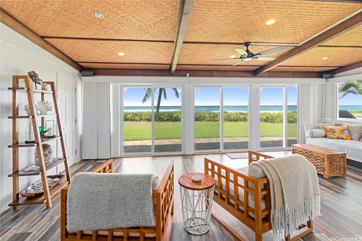 The large, open, and airy living room captures stunning ocean views, creating a seamless connection between indoor comfort and the natural beauty outside. Designed for relaxed coastal living, this bright space is perfect for gathering, entertaining, or simply unwinding by the sea. North Shore Haleiwa Hawaii.