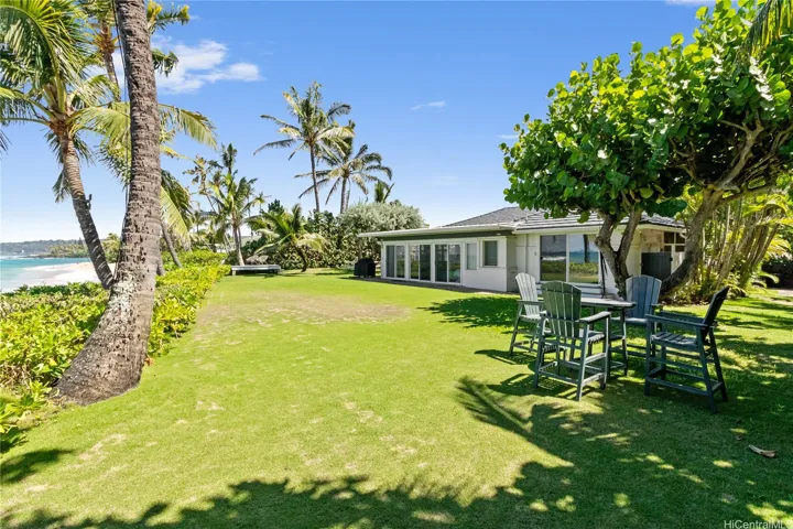 With 119 feet of beachfront yard, this property offers rare, wide-open ocean access—ideal for launching into water adventures or simply soaking in panoramic views. The expansive, grassy frontage is also perfect for a casual putting game, beachside lounging, or entertaining with the sound of waves as your backdrop. North Shore Haleiwa Hawaii.