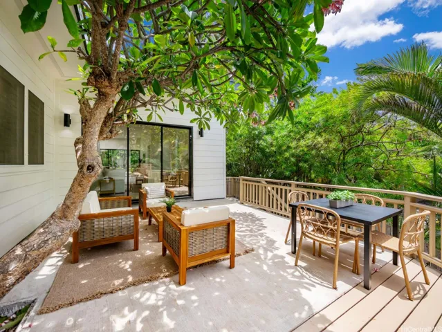 A fragrant plumeria tree grows through the lanai, creating a one-of-a-kind focal point in this spacious outdoor living area—perfect for both lounging and dining amid the lush surroundings.