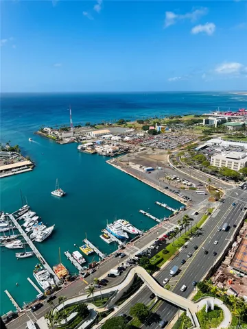 The new Victoria Ward Park with pedestrian bridge to the harbor are in the foreground, with the Waianae Mountains and ocean horizon in the background.