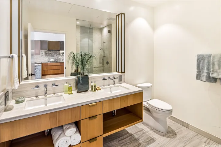 A beautiful spa-like bathroom features double sinks, a luxurious shower and good storage.
