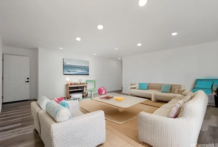 Enhanced photo of downstairs living room with virtual staging. Door to the left leads to the third bedroom