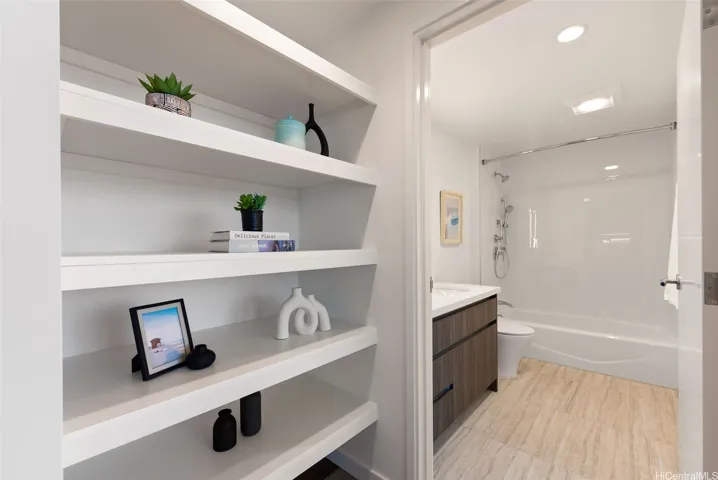 Built-in shelving provides stylish storage beside the full bathroom featuring a modern vanity and tub/shower combination