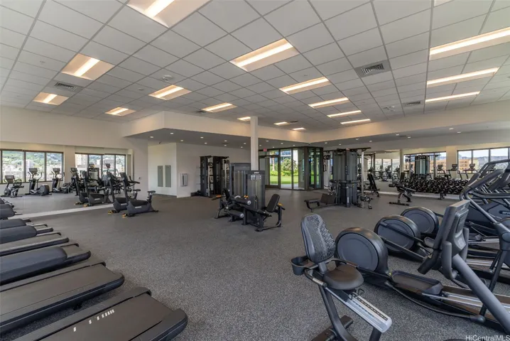 Spacious, fully equipped fitness center with cardio machines, strength-training equipment, and abundant natural light.