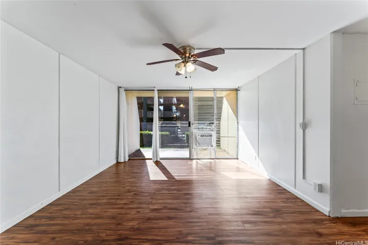 Another angle of the living room highlighting the long layout and sliding glass doors that bring in natural light.