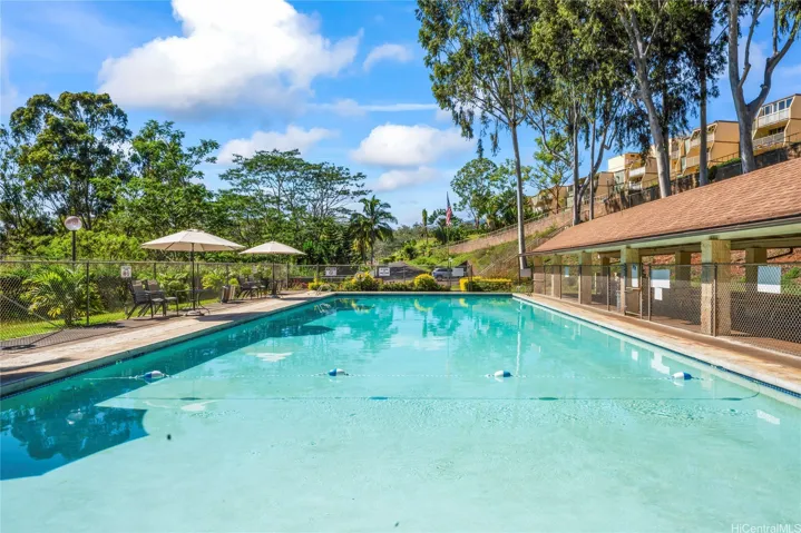 A resort-style community swimming pool with lounge seating and lush greenery.