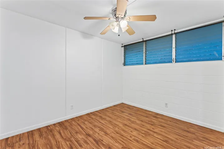 Second bedroom with wood flooring and high windows that provide natural light and ventilation.