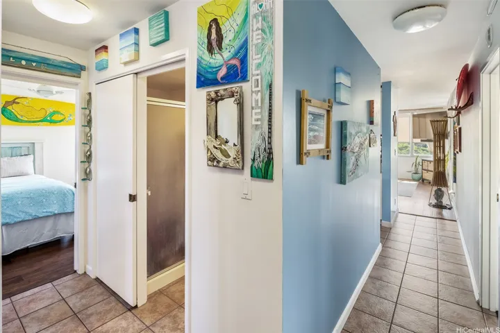 Welcoming entry hallway with the guest bedroom and bath to the left, and a clear path straight ahead to the primary suite, kitchen, living room, and lanai.