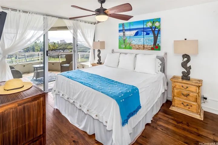 Inviting primary suite with warm wood floors and direct access to the lanai, so you can step outside and enjoy the breeze and views right from your bed.