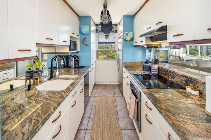 Updated galley kitchen with rich granite countertops, ample cabinet storage, and a window that brings in natural light and a refreshing cross-breeze while you cook.