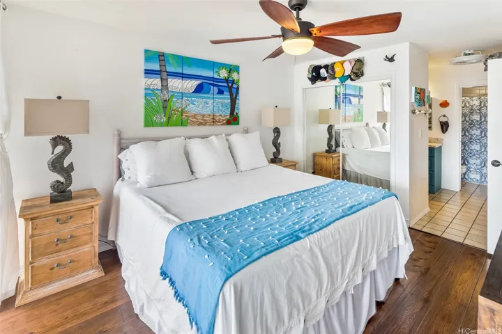 Stepping in from the lanai, the primary bedroom feels like a private retreat with warm wood floors, coastal décor, and plenty of space to relax and unwind.