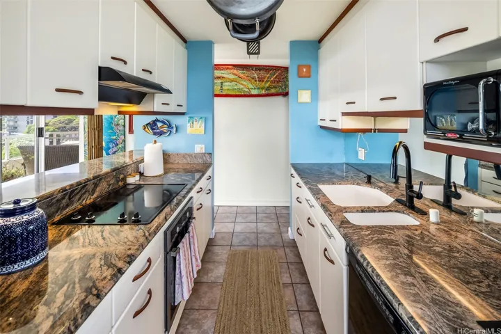 Cozy galley kitchen with rich granite counters and ample cabinet space, shown from the opposite direction to highlight the efficient layout and easy flow into the main living area.