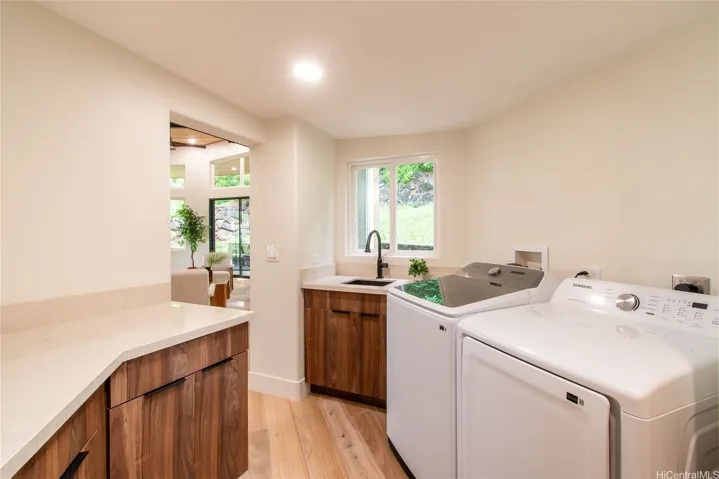Laundry room with high-end finishes, matching cabinetry, and a door to the backyard