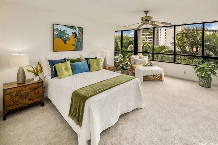 The Primary Bedroom is fresh and bright with new carpet and a wall of windows looking out at the greenery.