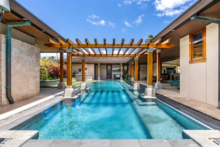 Enter into the private pool courtyard surrounded by covered seating, tropical flowers and an outdoor BBQ area.